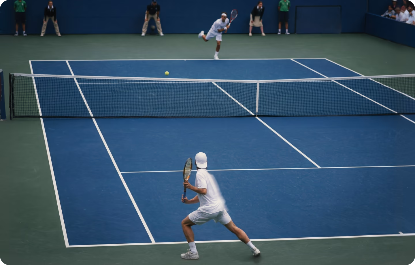 Two players in a rally on an indoor blue tennis court